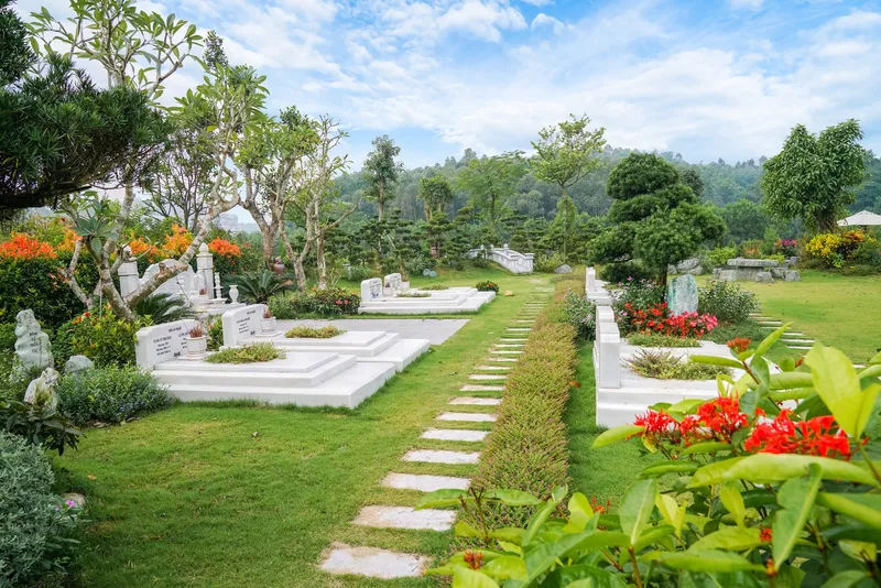 Khuôn viên gia đình có mộ đá trắng và hoa đỏ tại Công viên Thiên Đức