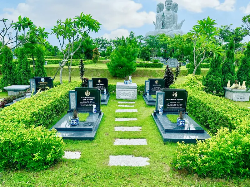 Khuôn viên gia đình nhỏ với bốn ngôi mộ đá và hàng rào cây tại Công viên Thiên Đức