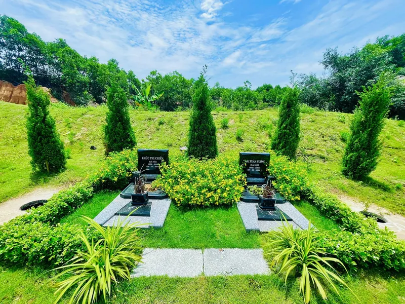 Mộ đôi đá đen có hàng rào cây xanh tại Công viên Thiên Đức