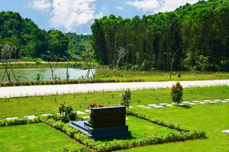Mộ đơn giữa thảm cỏ và hàng cây tại Công viên Thiên Đức